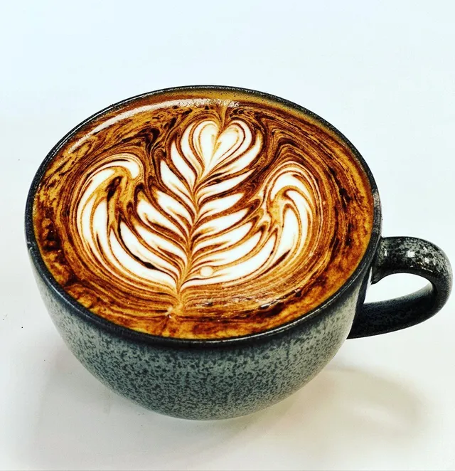 Flat white with latte art in a stoneware cup at The Happy Cup Cafe